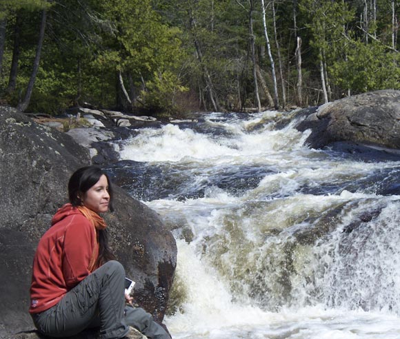 Photo of Édith Bégin, in the forest, in front of a waterfall